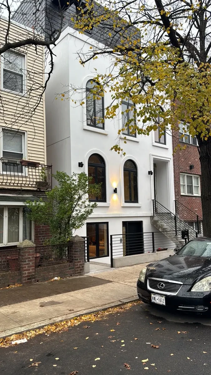 White stucco row house facade in Brooklyn seen from the sidewalk