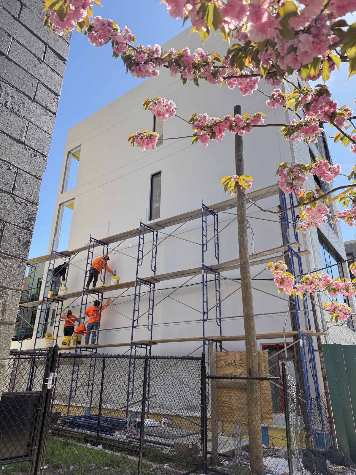 MNM crew applying stucco finish coat from scaffolding on a Brooklyn building